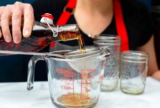 Straining homemade vanilla into a measuring cup.